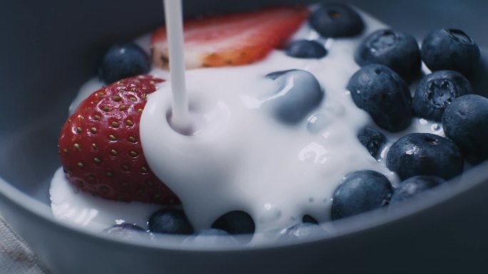 将天然有机牛奶或酸奶倒入装有新鲜有机水果和浆果的陶瓷碗中. 
