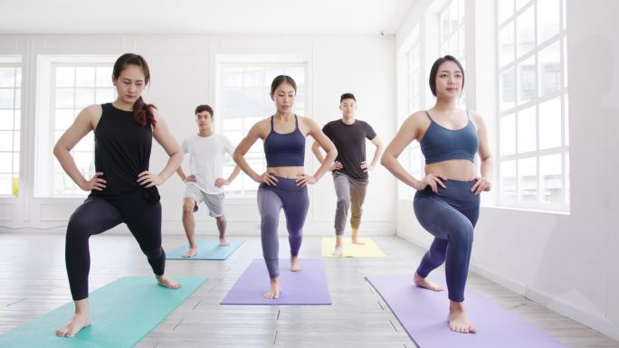 年轻有魅力的亚洲运动员和教练一起练习瑜伽。在健身室锻炼健康生活方式的亚洲妇女群体。体育活动、体操或芭