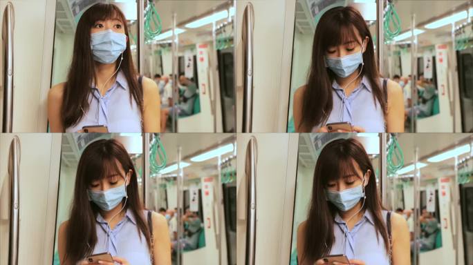 在地铁列车上，年轻的亚洲女性乘客戴着外科口罩，通过手机听音乐