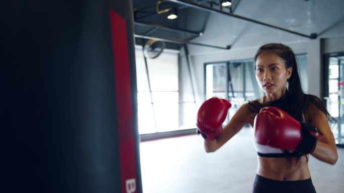 在健身课上，年轻的亚洲女子跆拳道练练习袋，强壮的女战士练拳击。女运动员娱乐活动、功能性培训、健康生活