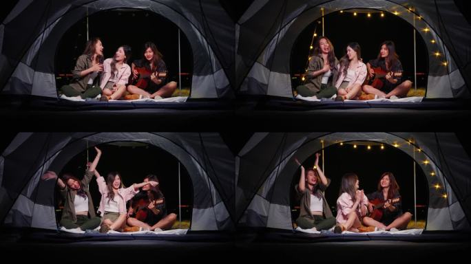 一群年轻的亚洲朋友在夏令营期间弹吉他，在帐篷里唱歌。自由,休闲,旅行,冒险的概念