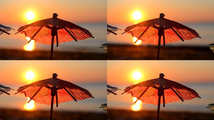 日落时分，海滨沙滩上的纸制鸡尾酒雨伞.