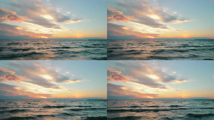 色彩艳丽的落日下,风景如画的海景尽收眼底.在明媚的日落时，海浪在海面上反射的缓慢运动，伴随着粉色的云