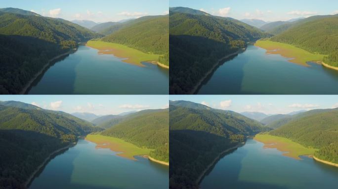 高山峻岭间覆盖着茂密的常绿森林，空中俯瞰蓝水清澈的大湖泊.