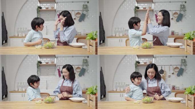 亚洲人在家里的厨房里快乐地做饭.母亲和儿子正在互相帮助做沙拉.家庭关系