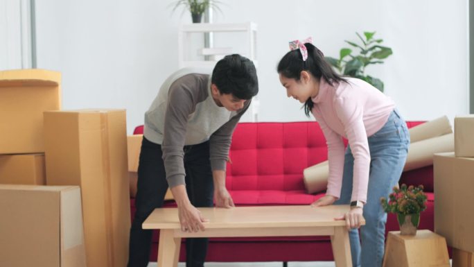 亚洲夫妇背着大木桌决定在新家装修。搬家。搬迁和欢迎。幸福的夫妇搬进新家。