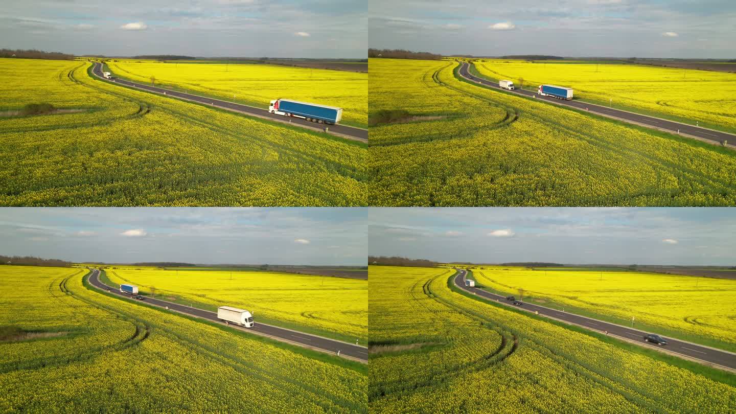 售后服务：货车和汽车在经过黄土的高速公路上行驶。美丽的乡村沥青路面上，环绕着盛开的甘蓝菜农田，交通繁
