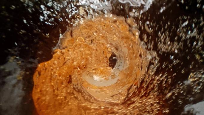 酒，烈酒，晚上好威士忌被倒入一个装有冰块的杯子，慢动作，宏观摄影，木制桌子和黑暗的背景。倒威士忌或朗