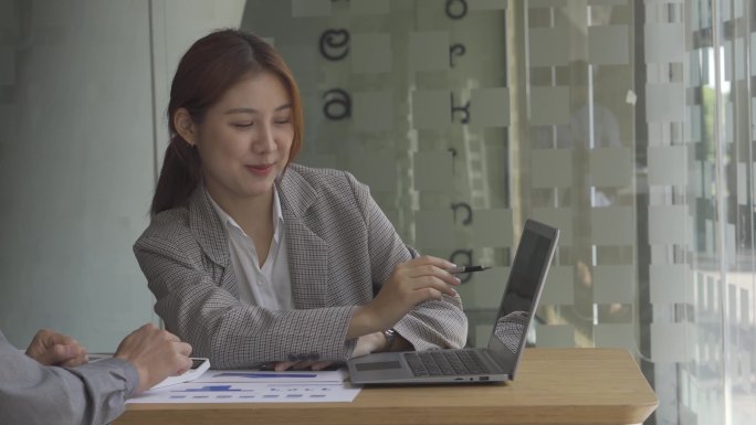 在办公室里从事财务会计工作的亚洲妇女，在商业概念表的计算分析中使用笔记本电脑和图形化文档.