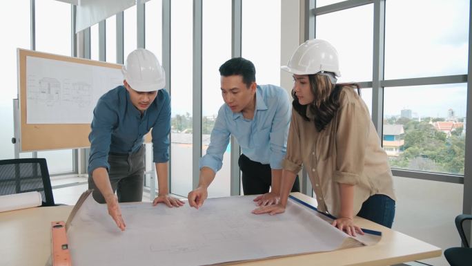 亚洲集团的设计师们在办公室的商务会议桌上制定了一个蓝图，建筑师们在讨论业务计划.