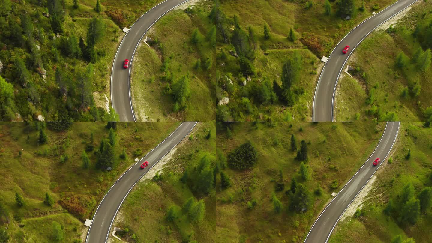 红色汽车在弯曲的道路上行驶，蜿蜒在高地的针叶林山坡上。风景秀丽的林山中的蛇形高速公路鸟瞰图