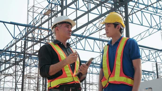 两名白人和亚裔工程师与土木工程师讨论建筑工地的建设计划、房地产项目.