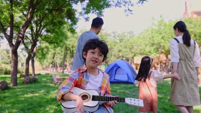 男孩坐在露营车上弹吉他全家开心转身打招呼