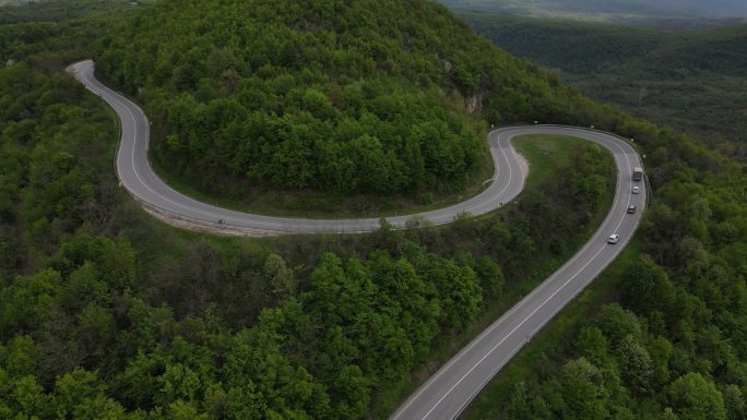 空中俯瞰公路上的汽车在春天的日子里穿过山脉的树木。塞尔维亚的Tresibaba Knjazevac。