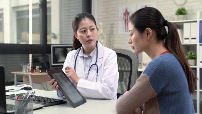 现代亚洲女医生用片剂来显示 x 光图片, 以解释病人的健康状况。.