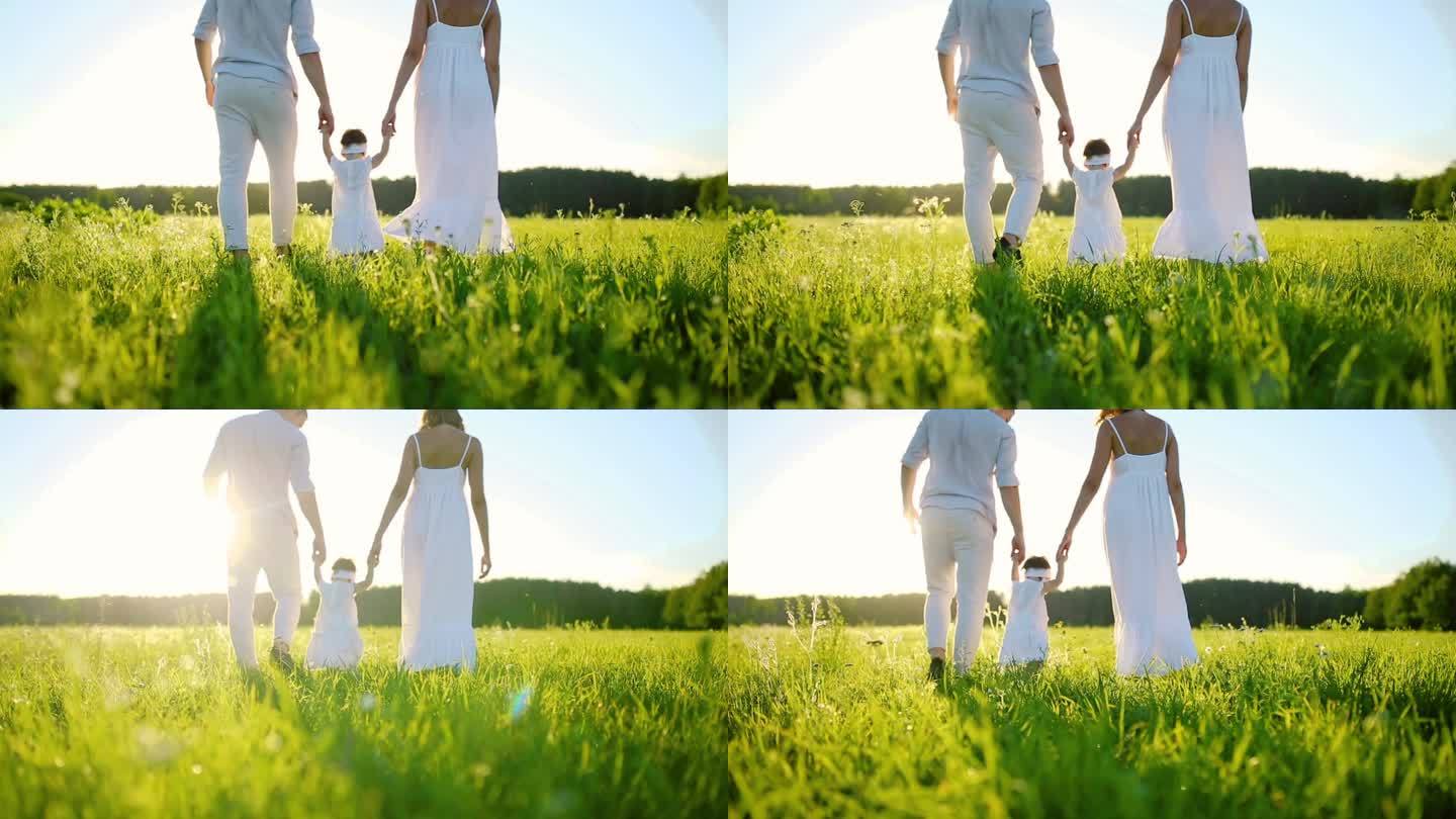 家人走在公园里和她的第一步的宝贝女儿。都穿白色，夕阳下.