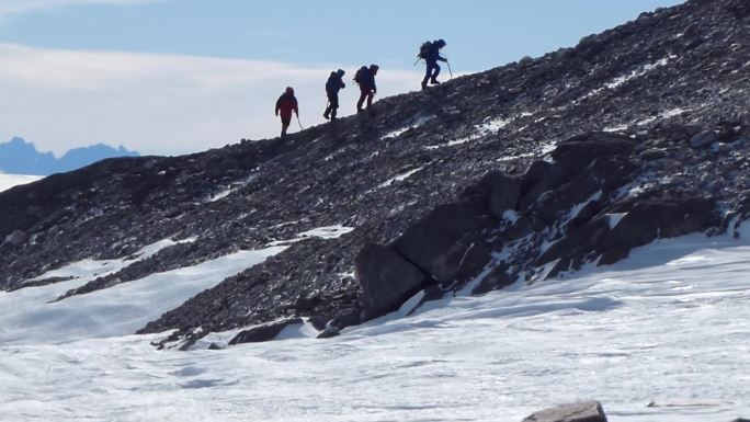 登山者攀登山与雪场。四个登山者登山