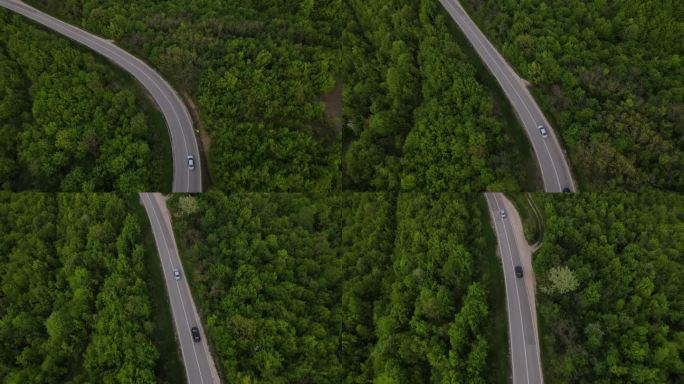 在塞尔维亚，春车沿着蜿蜒的公路行驶时，在山脉上一条弯曲的沥青路面的空中无人驾驶镜头，周围环绕着绿地和