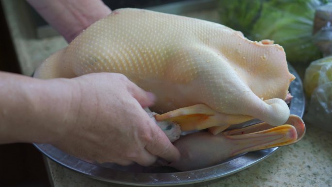 厨房里一位厨师在备菜，腌制一整只鸭子