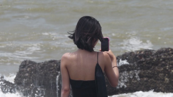 拿手机站在海边的女子