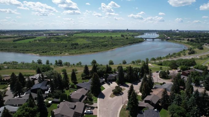 无人机拍摄的加拿大萨斯卡通郊区住宅和蓝天池塘边的草坪