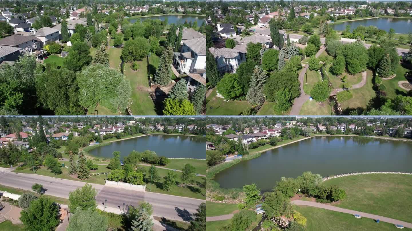 无人机拍摄的加拿大萨斯卡通郊区房屋和树木，旁边是一个小池塘，天空一片蔚蓝