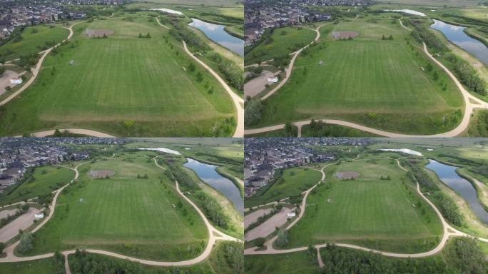 无人机拍摄的加拿大萨斯卡通郊区房屋和池塘边的绿色草坪