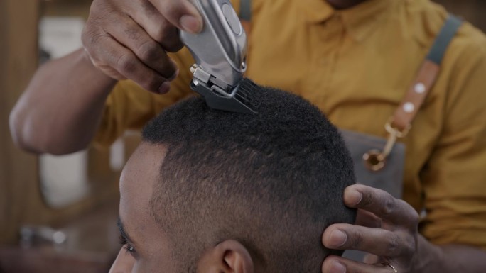 理发师在理发店用电动机器和顾客一起剃须的特写
