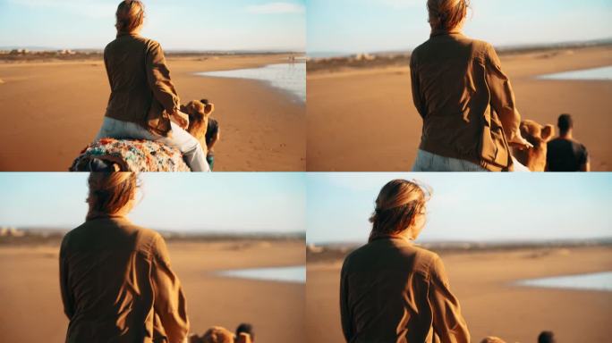 慢镜头:女游客在导游的带领下骑骆驼在沙滩上