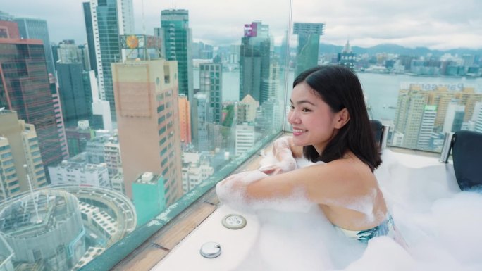 来香港旅游的女孩和私人屋顶房间的按摩浴缸。香港的高楼大厦。