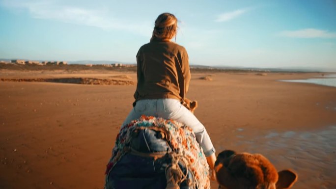 在撒哈拉沙漠上骑骆驼的女游客