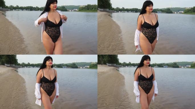 一个30岁的大码模特穿着黑色内衣和白色衬衫走在海边。暑假在海滩上，胖的黑发女人，长头发