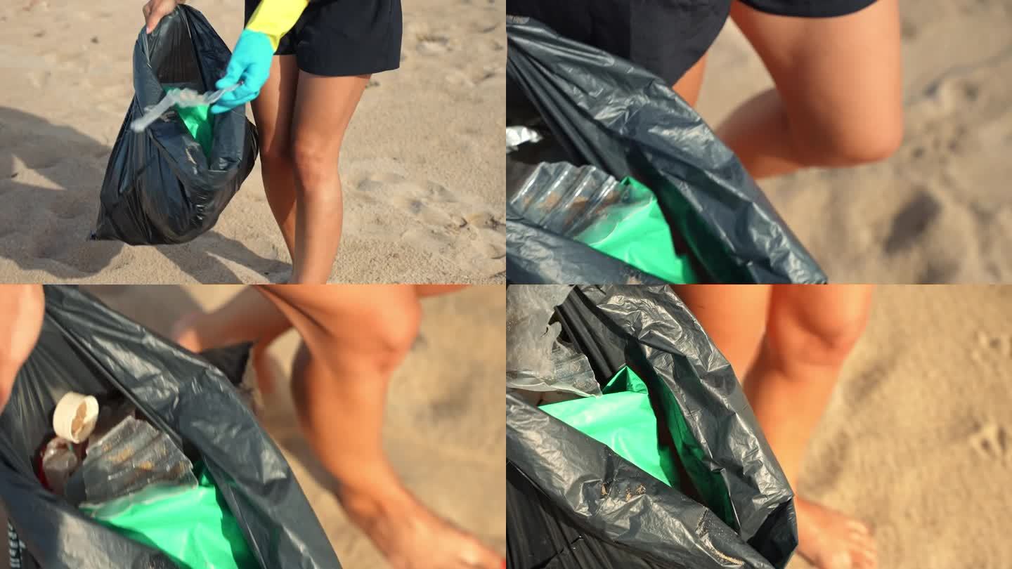 年轻女子戴着防护手套从海滩上捡垃圾，把垃圾放进垃圾袋里