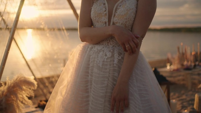 浪漫优雅的新娘在蕾丝白色婚纱，婚礼在沙滩上的日落，肖像