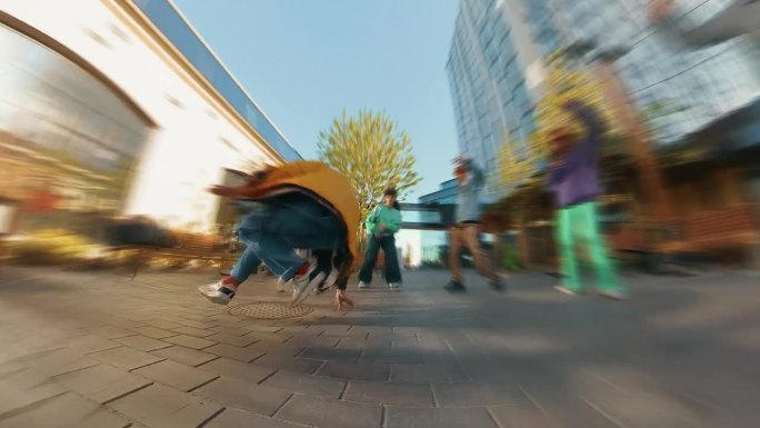 时髦的变焦模糊编辑年轻时尚的B-boy霹雳舞在城市街区的现代建筑之间。一群朋友在后台欢呼，支持霹雳舞