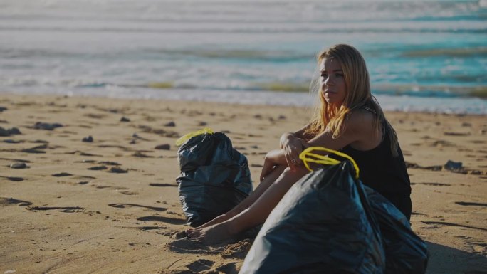 在清理了一整天的海滩塑料后，一名女子在阳光明媚的海滩上放松