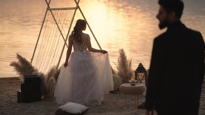 浪漫的婚礼在沙滩上的夕阳，剪影的新娘和新郎，爱的人，后视图