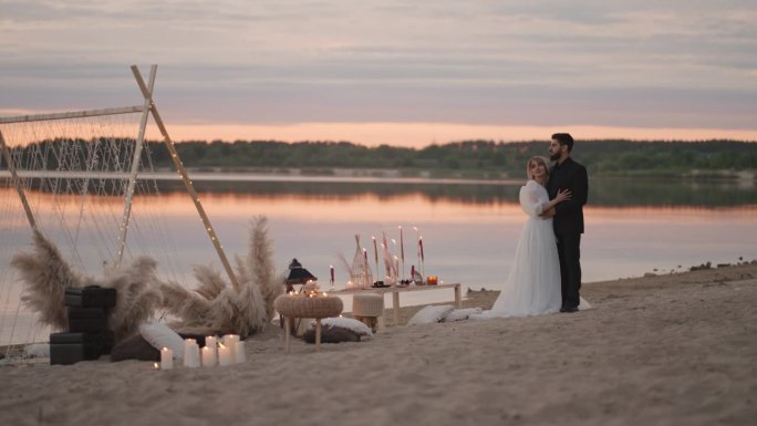 在夕阳下的沙滩上，一对幸福的新婚夫妇举行了婚礼，男人和女人拥抱在一起