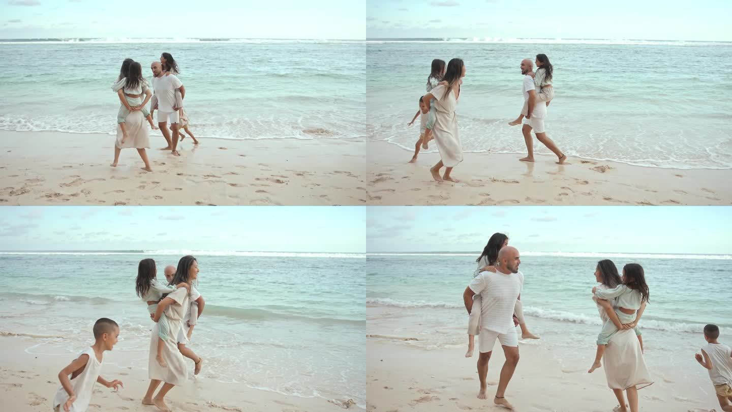 一男一女抱着孩子，在海滩的海水中嬉戏的快乐家庭。小孩子在热带海岸和爸爸妈妈一起玩耍。健康人的生活观—