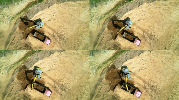 航拍画面显示，一辆建筑工地的挖掘机正在将沙子装进一辆卡车