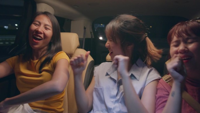 一群年轻的亚洲朋友一起跳舞，一起玩，晚上开车在城市里自驾游到暑假。汽车旅游目的地。