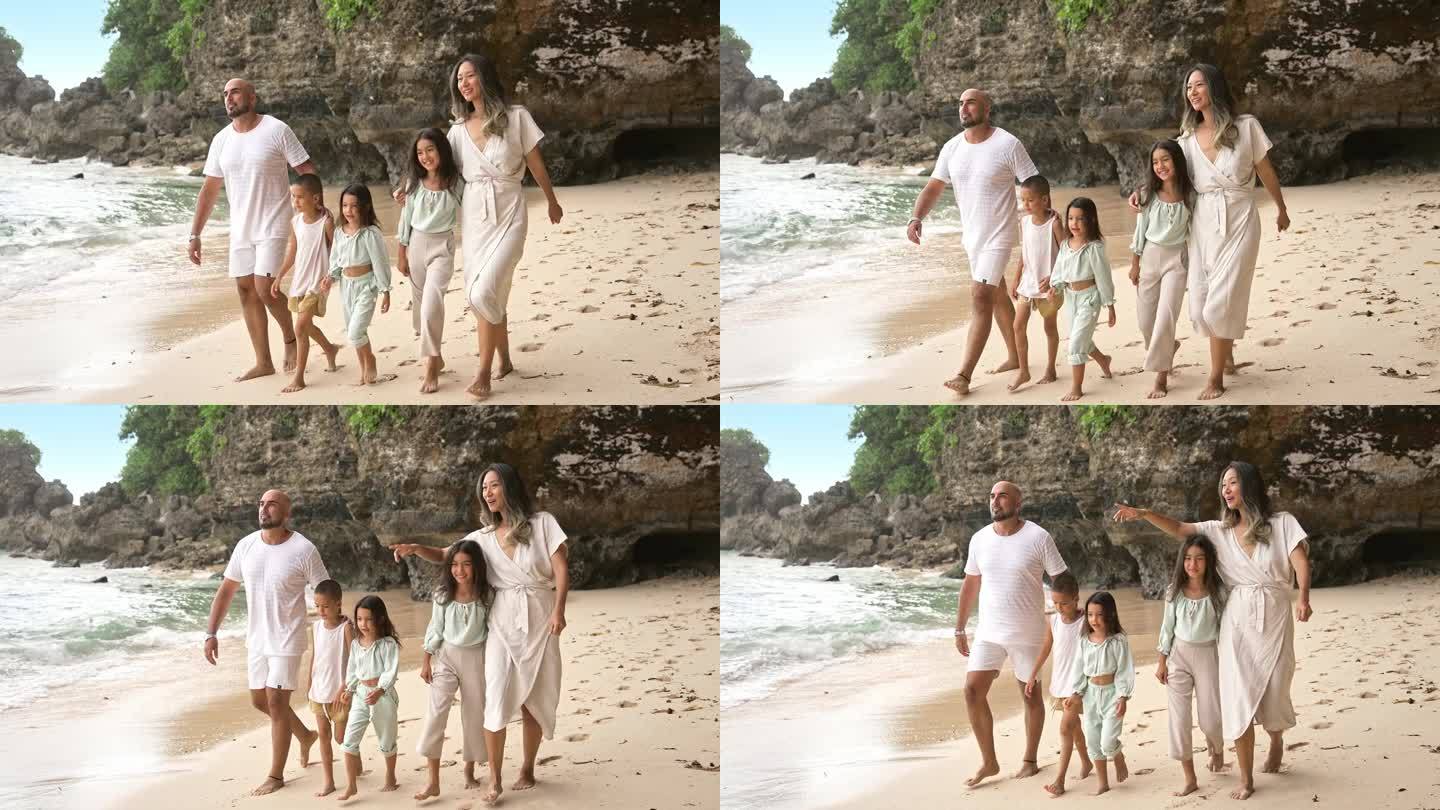 一男一女带着孩子在海滩和海水边散步的快乐家庭。小女孩和男孩的热带旅游与爸爸妈妈在岸边放松。健康美与人