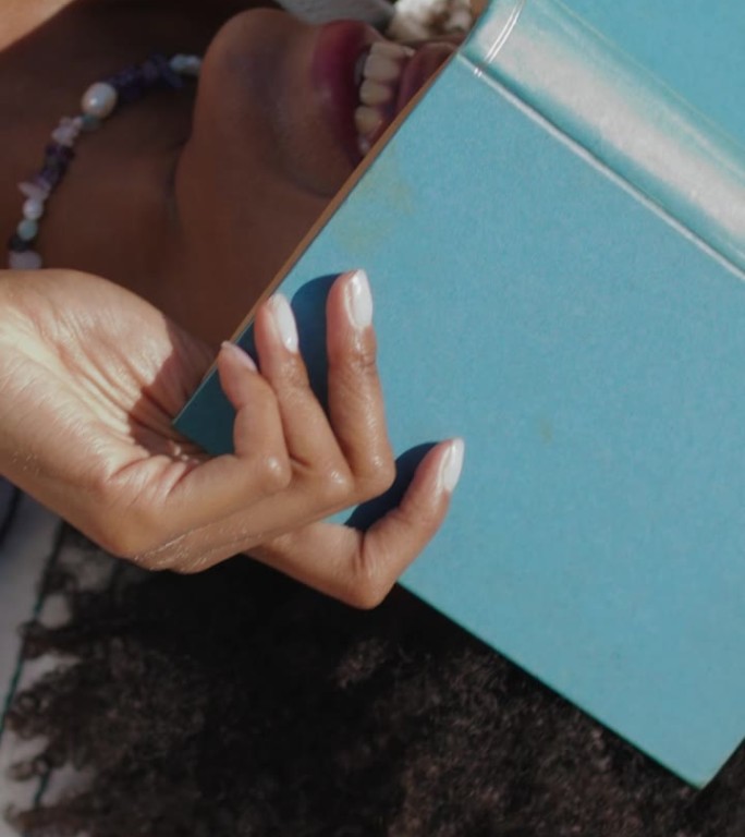 女孩把脸书藏在沙滩上休息。垂直视频俏皮女人