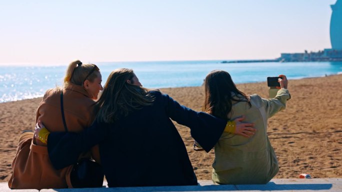 三个女性朋友在巴塞罗那海滩上自拍。只适合女孩的旅行。让记忆