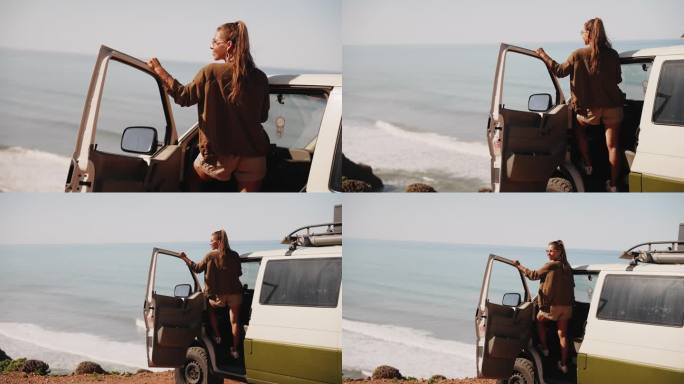 一名女子站在沙滩上露营车的门边，向外眺望海湾