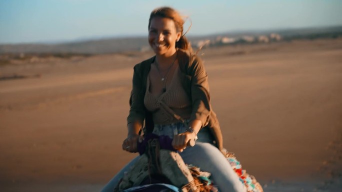 在沙滩上骑骆驼的女游客