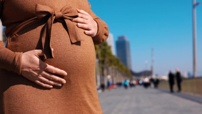 一名孕妇在巴塞罗那海滩的长廊上抚摸着自己的肚子