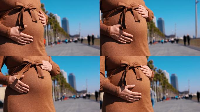 一名孕妇在巴塞罗那海滩的长廊上抚摸着自己的肚子