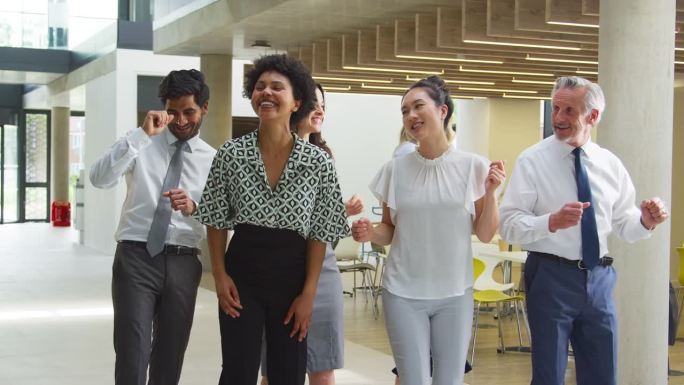 微笑的多元文化商务团队在办公室大堂欢舞