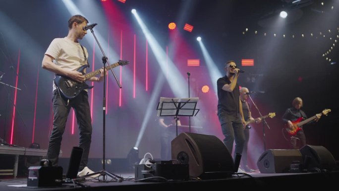 现代流行乐队主唱吉他手和键盘手在夜总会的舞台上表演。慢动作